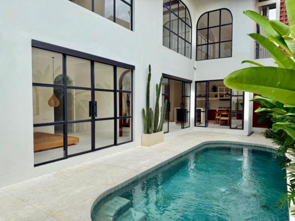 Courtyard pool surrounded by glass doors and tropical landscaping